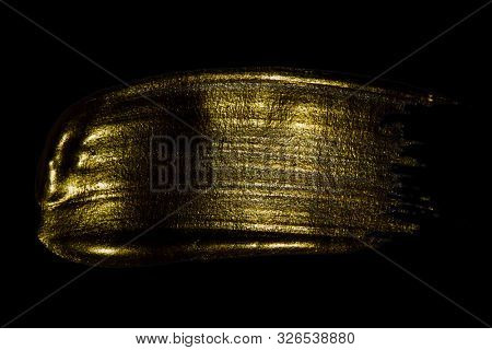 Creative brushstrokes of gold paint isolated on a black background. Gold paint texture.Acrylic gold paint. Smears of cosmetics, blush, highlighter, eye shadow, lipstick.
