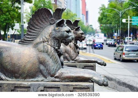 Mexico City / México - March 20, 2016: Pair Of Female Lion Statues Wearing A Crest Of Plumes On Monu