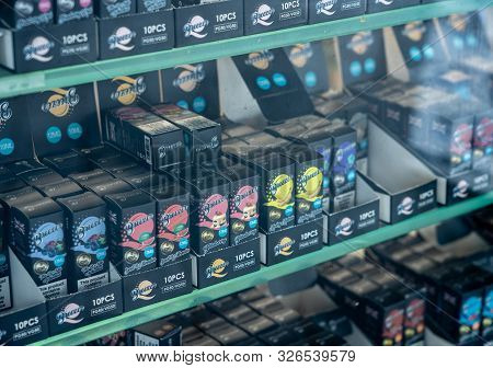 London, Uk - 4 October 2019: Many Brands Of Flavored Nicotine For E-cigarettes In Shop With Reflecti