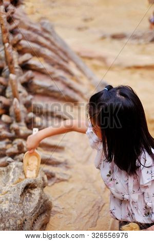 A Cute Asian Girl Playing In A Sandbox With A Modeled Dinosaur Fossil