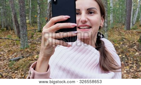 A Young Woman Takes Selfie On The Phone With Pleasure In The Spring Forest And Smiles. Slow Mo. Clos