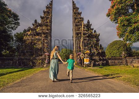 Mother And Son Walking Through Traditional Balinese Hindu Gate Candi Bentar Close To Bedugul, Bratan