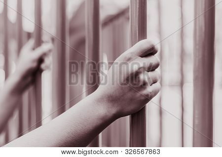 Prison Hands Holding Steel Cage Jail Bars. Offender Criminal Locked In Jail Red Colour Tone.