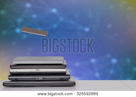 Stack Of Laptop Computers And A Smartphone. A Pile Of Computers And A Smartphone On A Bright Table A
