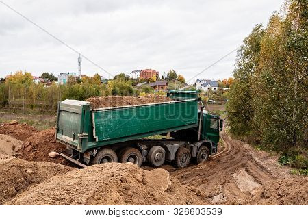A Large Green 70-ton Dump Truck Brought Sand To A New Construction Site To Add Land