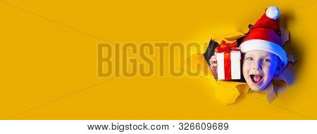 Little Cheerful Santa Gives A Gift, Getting Out Of The Ragged Yellow Background