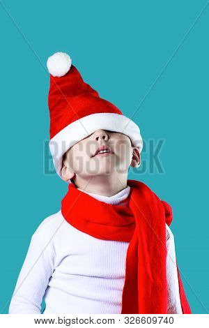 Merry Little Santas Hat Fell Down Over His Eyes. A Red Scarf Is Tied Around His Neck. On Blue Backgr