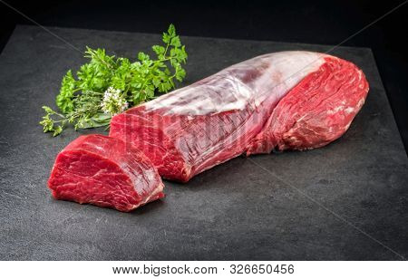 Dry aged beef fillet steak natural with a bouquet garni as closeup on black background with copy space