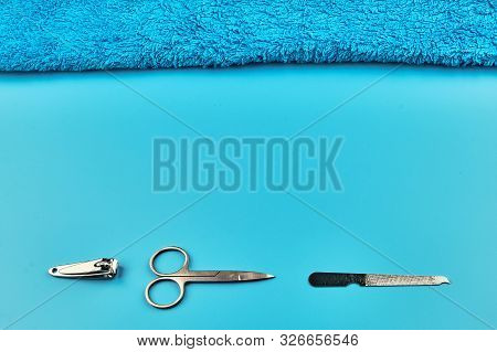 Metal Manicure Tools With Towel On Blue Background, Flat Lay With Copy Space