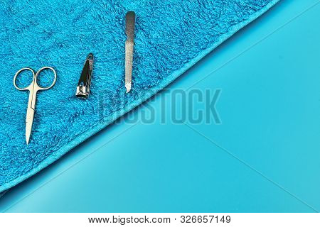 Metal Manicure Tools With Towel On Blue Background, Flat Lay With Copy Space