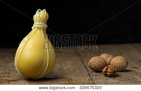 Typical Italian Cheese Caciocavallo With Walnuts On A Wooden Surface. On A Dark Background.