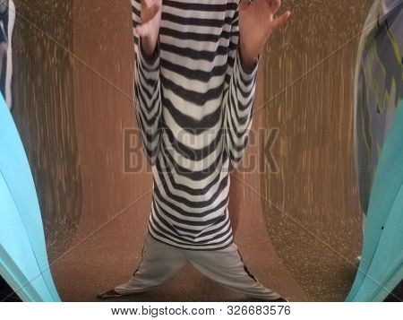Child With Black And White Shirt Distorted In Fun House Mirror