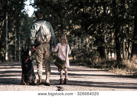 Back View Of Man Holding Hands With Kid Near German Shepherd Dog, Post Apocalyptic Concept