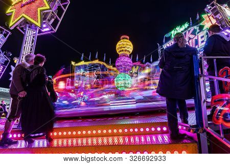 Munich, Germany, 2019 September 24: Visitors Enjoy The View Of An Amusement Park Ride At Night. Brea