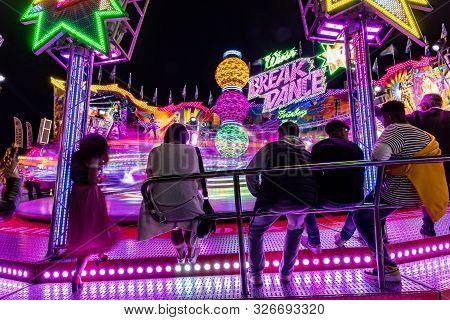 Munich, Germany, 2019 September 24: Visitors Enjoy The View Of An Amusement Park Ride At Night. Brea