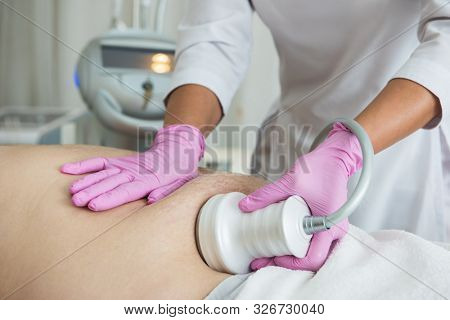 Closeup photo of fat man with big belly having cavitation procedure removing cellulite on abdomen in modern beauty clinic