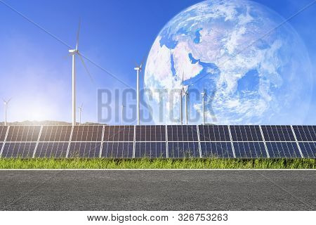 Asphalt Road With Solar Panels With Wind Turbines Against Mountanis Landscape In Earth Blue Sky With