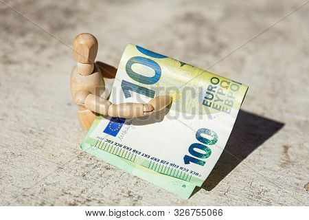 Wooden Dummy Puppet Holding Hundredth Euro Banknote. Money Or Business Concept. Abstract Conceptual 