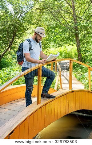 Young Man Hiking Living Healthy Active Lifestyle. Bearded Man Traveler With Backpack Reads A Map Out