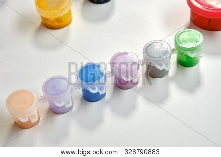 Colorful Paints Are Standing On A Table With A Whatman. Art Studio. Isolated On White Background. Me