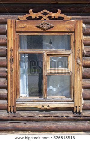 Window With Carved Platbands In An Old Wooden House.