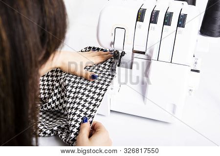 Overlock. The Woman Sews The Knit Fabric On The Overlock