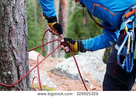Male Hands In Gloves Checks Safety During Preparation For The Descent From The Cliff. Climber In A B