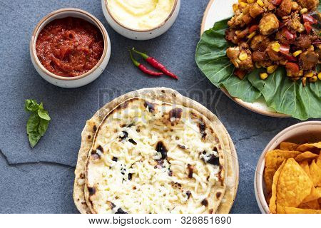 Mexican Cuisine On A Gray Stone Background. Homemade Buritto With Cheese, Nachos Chips With Tomato A