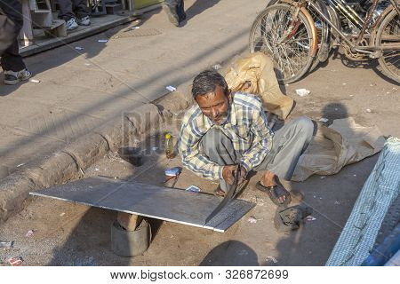 New Delhi, India - Nov 17, 2011: Man With Saw Cuts A Rigips Plate At The Street In Old Delhi, Chawri