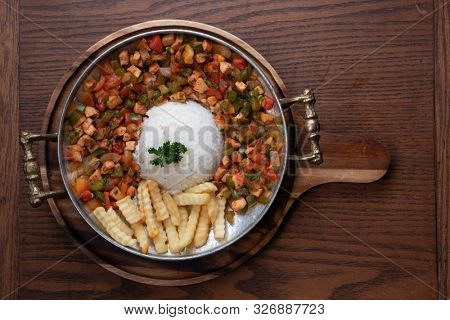 Turkish food lamb meat saute, sac kavurma with rice and french fries isolated on rustic wooden table