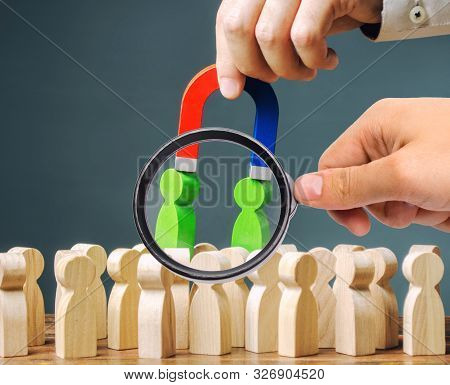A Magnifying Glass Looks At A Magnet Pulls Green Figures Of People Out Of The Crowd. Recruiting New 