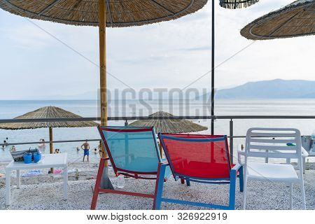 Two Empty Chairs With View At Beach Bar Overlooking Mediterranean, Greece.