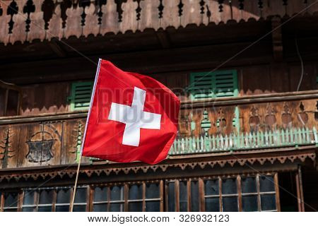 Swiss Flag In Front Of A Traditionnal Mountain Chalet