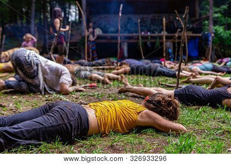 An Intergenerational Group Of People Seeking Mindfulness Are Seen Laying Flat On Sacred Soil At A Fo