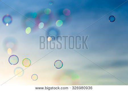 Colorful Soap Bubblesflying Towards A Blue And Orange Sky While The Sun Is Setting.