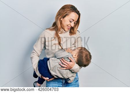 Young caucasian woman holding and hugging her son breastfeeding him, maternity lactation