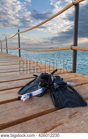Dive Mask, Swimfins And A Snorkel On Wooden Pier With A Sea On The Background. Travel And Vacation C