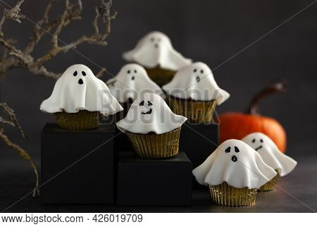 Halloween fondant ghost cupcakes on black podiums.  Halloween party food idea.