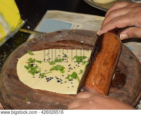Rolling Plain Naan (indian Bread) On A Circular Wooden Board Before Baking It