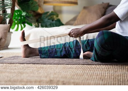 Young African Man Sitting In Janushirshasana Seated Forward Bend Posture At Home