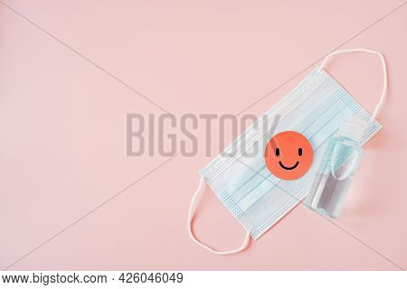 Pink Healthy Smiling Face Paper Cut On Medical Face Mask And Bottle Of Blue Alcohol Gel On Sweet Pin