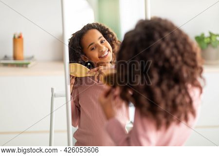 Morning Beauty Routine. Happy African American Girl Combing Her Curly Hair With Wooden Comb, Over Sh