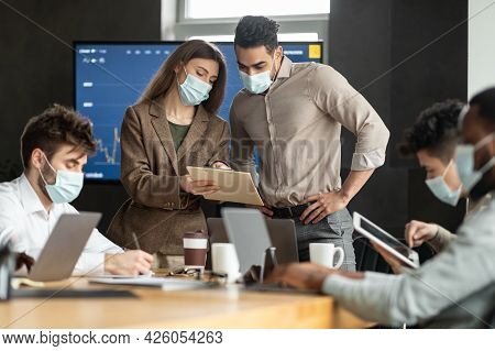 Coworkers Having Brainstorm Meeting In Boardroom, Woman Showing Documenation