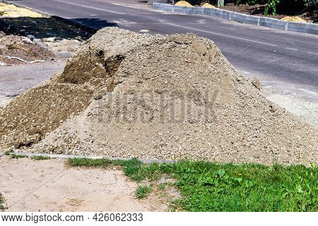 A Pile Of Sand-stone Mixture. Near Road. Asphalt. Grass. Green.
