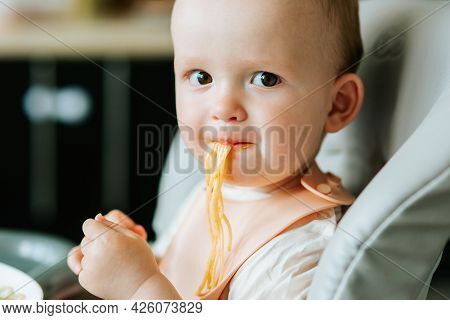 Close Up. Home In The Kitchen Little Boy Boy Eating Spaghetti Pasta With Red Sauce. Baby Boy Eating 
