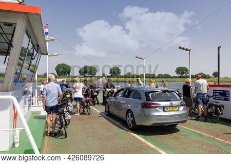 Cuijk, The Netherlands - June 18, 2021: Small Ferry With Cars, Bicycles And Pedestrians Over River M