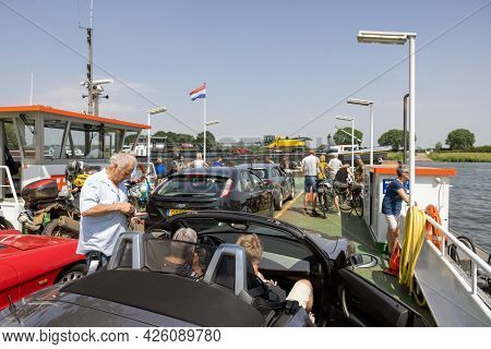 Cuijk, The Netherlands - June 18, 2021: Small Ferry With Cars, Bicycles And Pedestrians Over River M