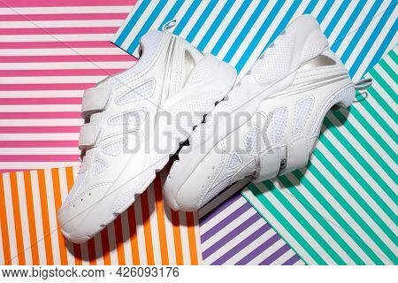 Top View Two White Kid Sneakers With Velcro Fasteners For Comfortable Footwear On An Abstract Geomet