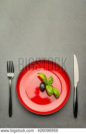 Diet. Small Amount Of Food On The Plate. One Olive Is In A Red Plate, A Knife And A Fork. Weight Los