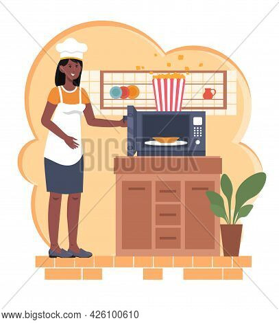 Cooking Popcorn At Home. A Woman In An Apron And A Chefs Hat Is Standing Next To The Microwave And P